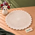 Side view of Aura Scalloped ivory round crochet table mat