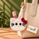 White Ayzalo Kitty crochet lip gloss holder with red bow shown in a lifestyle setting