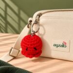 Red crochet octopus keychain shown as a single bag charm