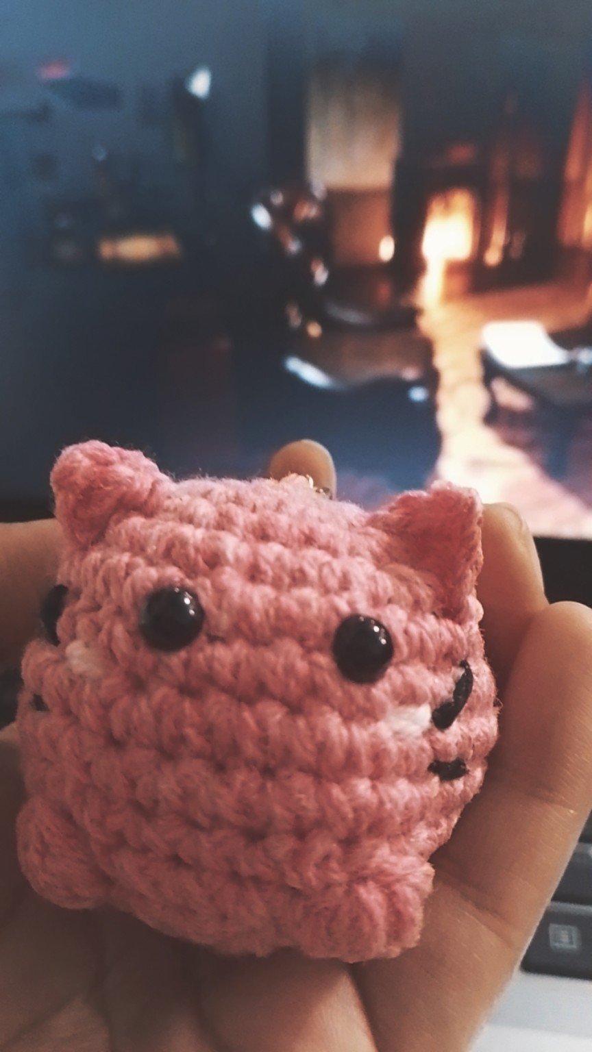 Small pink crochet cat with pointed ears and dark eyes