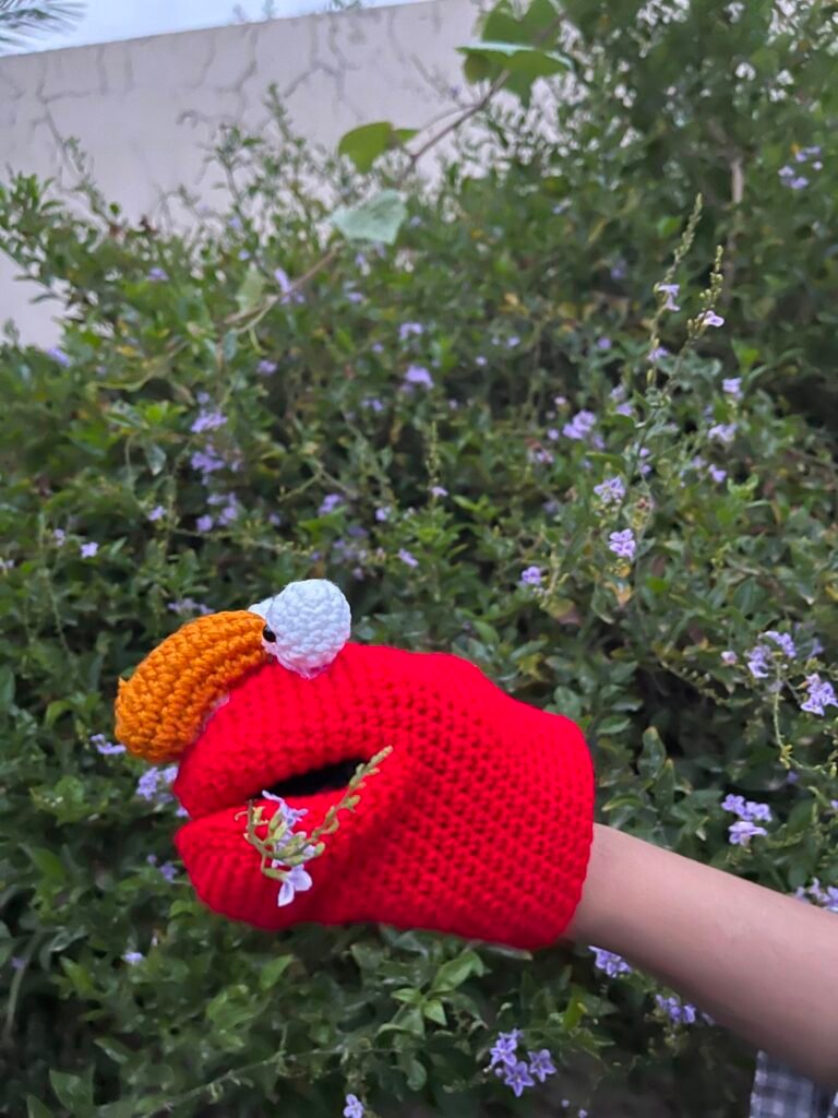 Red crochet hand puppet shown with its mouth open