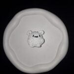 Small white crochet bear charm with black stitched facial details